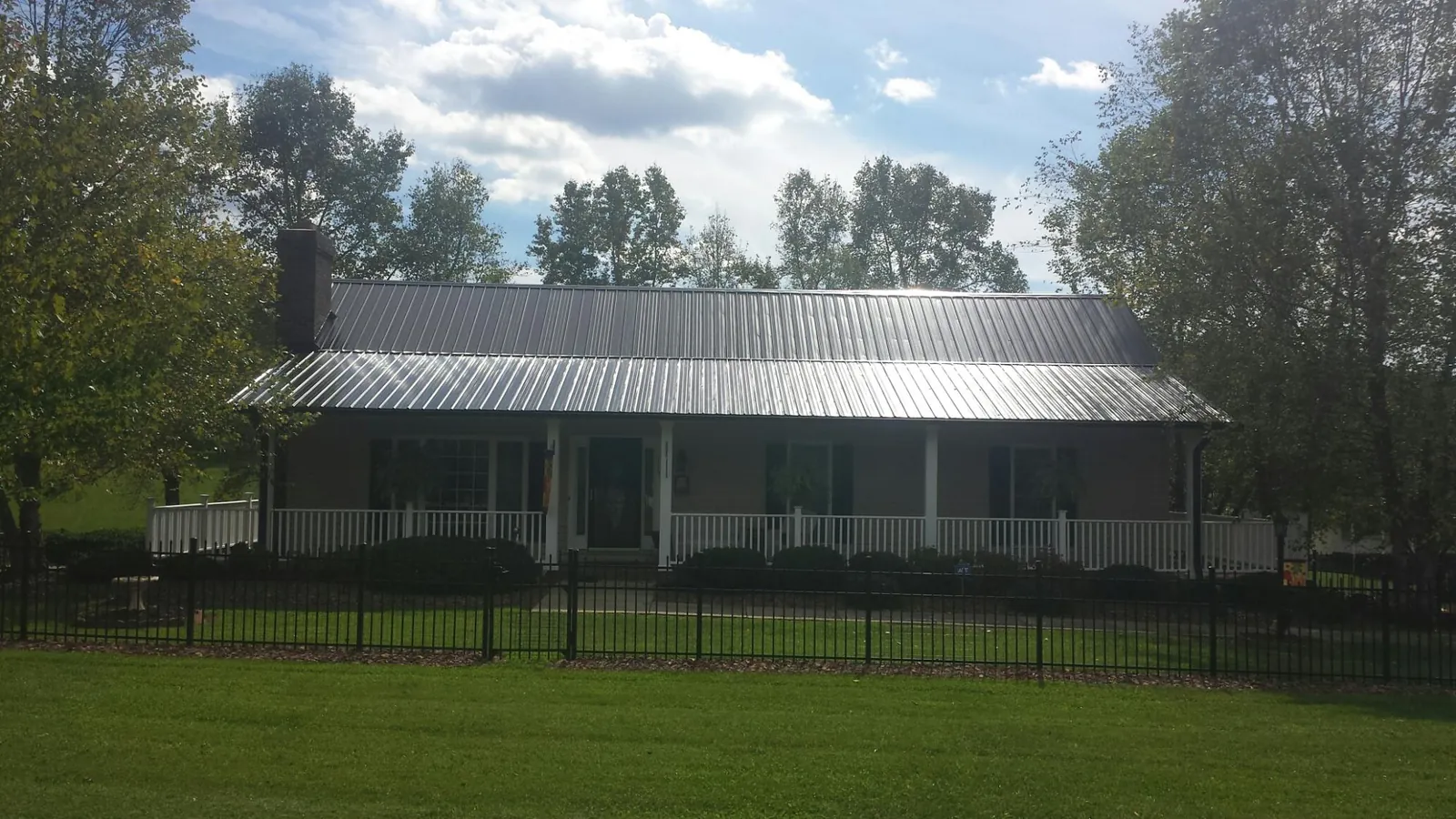 Gray metal roof on a brick ranch with a full width front porch — Gutter Guard Installation work by our crew in Denmark