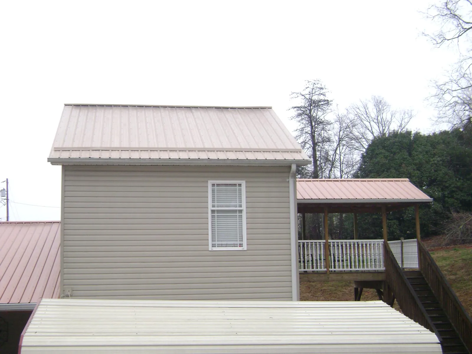 Tan metal roofs on a two story addition and attached porch, from a Roof Replacement job in Denmark