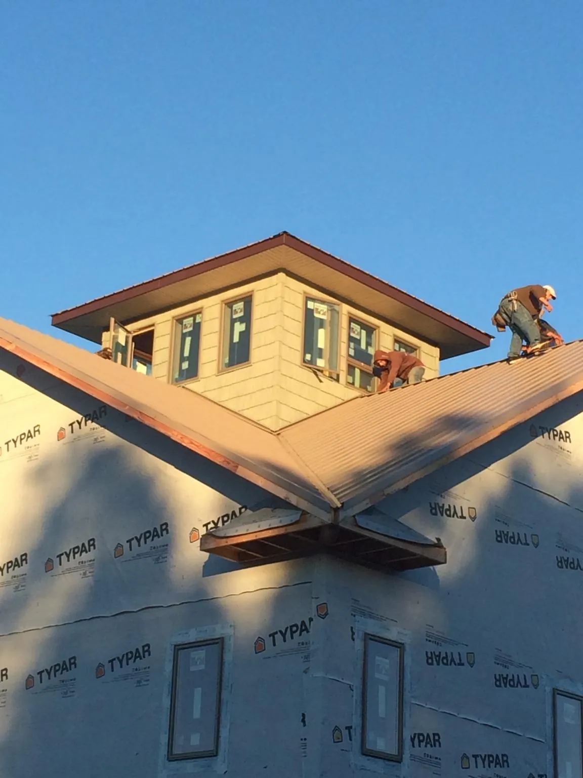 Roofers working around a rooftop cupola on a new metal roof at sunset — Roof Waterproofing in Denmark by Roofing Brothers
